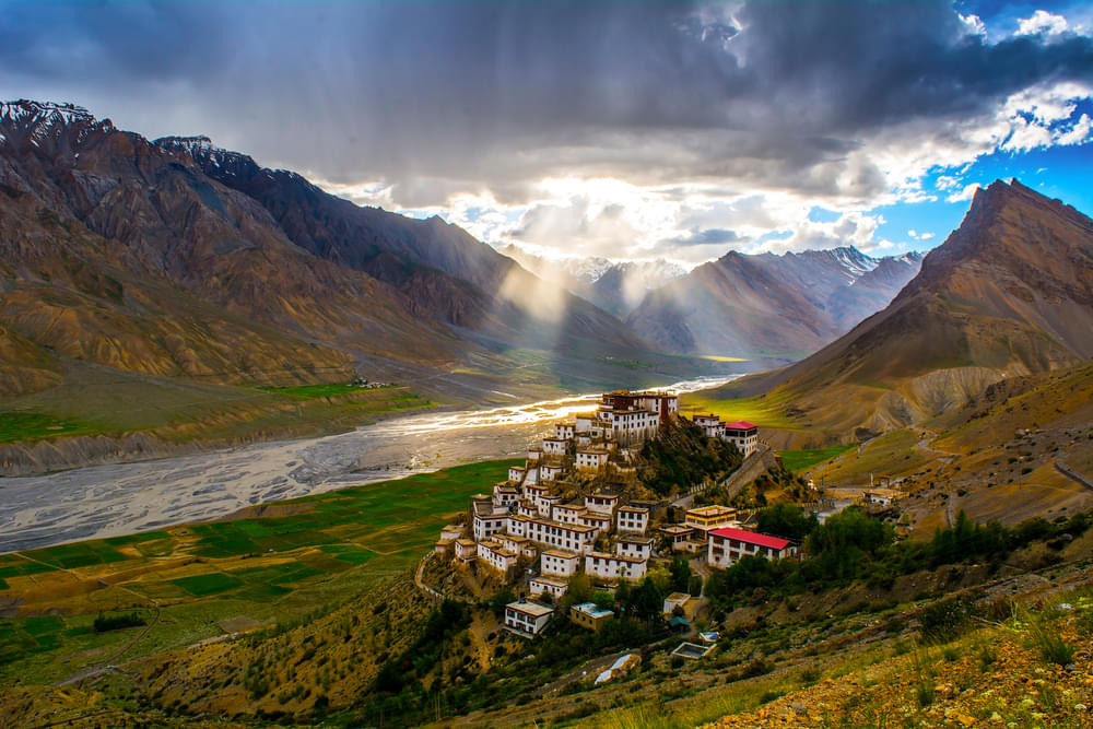 A man wrapped in a blanket gazes at the majestic mountains in the distance.